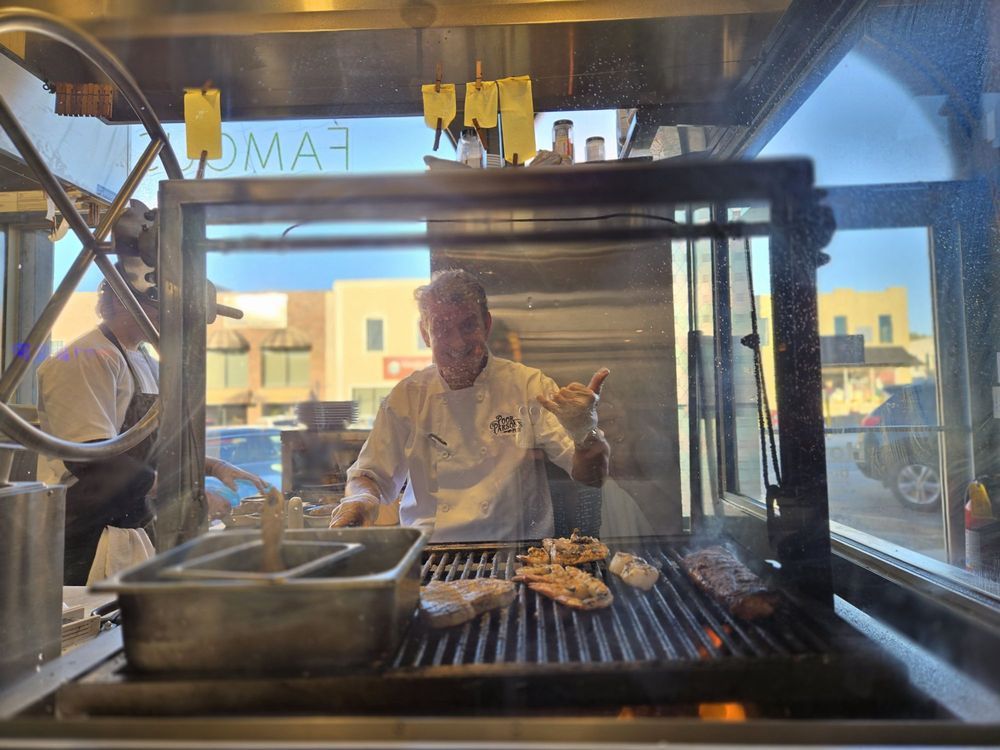 Chef grilling steaks over the wood-fired grill